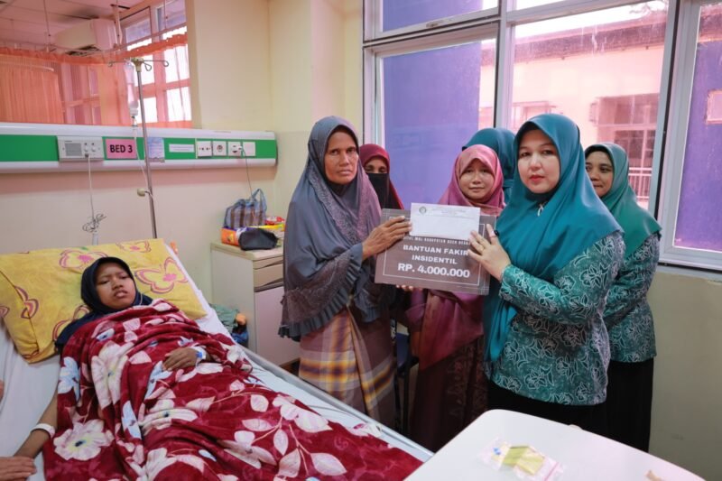 Ketua TP PKK Aceh Besar, Hj. Rita Mayasari menyalurkan bantuan fakir insidentil yang bersumber dari Baitul Mal Kabupaten Aceh untuk Sita Maisura(22) seorang mahasiswi yang kini terbaring sakit akibat penyakit aneh di RSUDZA Banda Aceh, Selasa (29/4/2025). FOTO/MC ACEH BESAR