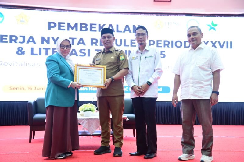 Bupati Aceh Besar Muharram Idris menerima sertifikat penghargaan dari Wakil Ketua LPPM Bidang Pengabdian kepada Masyarakat USK, Dra. Sulatri, M.Si saat pembekalan KKN Mahasiswa USK periode XXVI di Hall Gedung AAC Prof. Dayan Dawood, Banda Aceh, Senin (16/6/2025). FOTO/MC ACEH BESAR