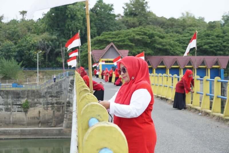 Ketua TP PKK Kecamatan Seulimeum, Evi Maidasri SE, memasangkan bendera merah putih di Jembatan Bendungan Krueng Aceh, Seulimeuem, Aceh Besar, Sabtu (16/8/2025). FOTO/ MC ACEH BESAR