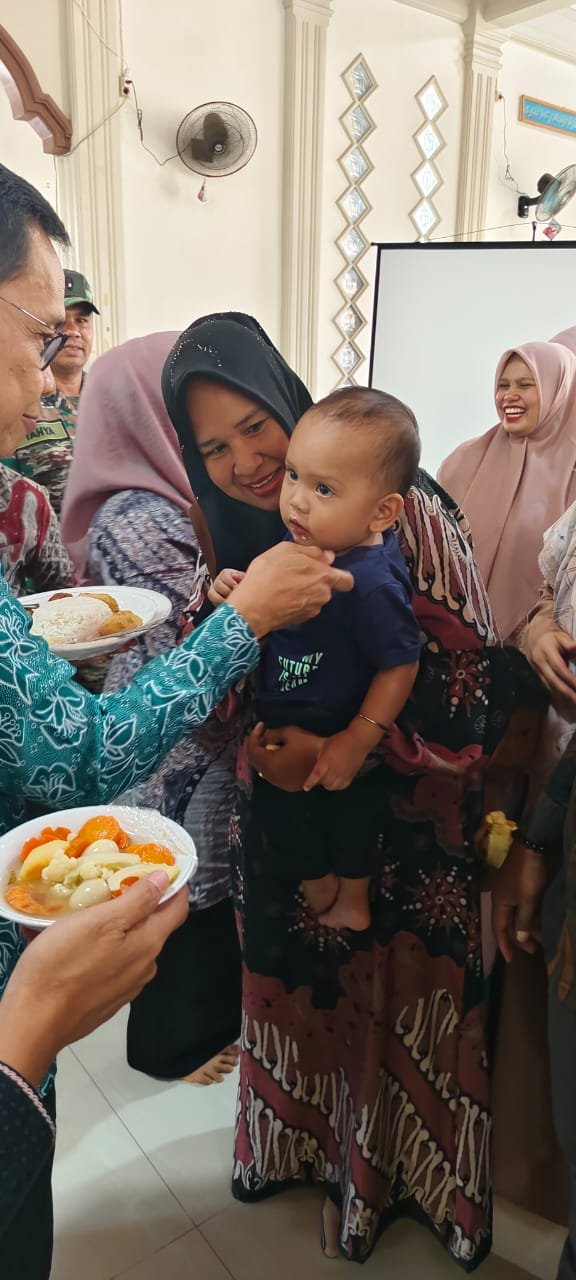 Ketua IV Bidang Kesehatan Keluarga dan Lingkungan TP PKK Aceh Besar, T. Raden Sulaiman, menyuapi seorang balita di Gampong Lheu Blang, Kecamatan Darul Imarah, Kabupaten Aceh Besar, Jumat (29/8/2025). FOTO/ MC ACEH BESAR