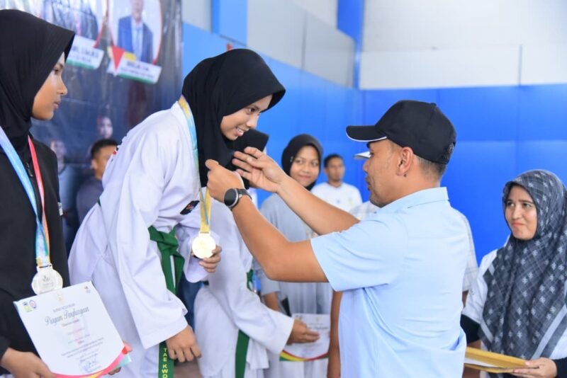 Ketua DPRK Aceh Besar Abdul Muchti mengalungi Medali kepada Juara Taekwondo PORKAB 2025 di JSC, Kota Jantho, Selasa (9/9/2025). Foto: Dok. Mc Humas Aceh Besar