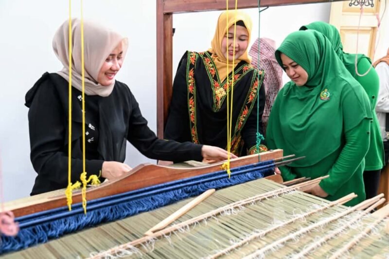Ketua Dekranasda Aceh Besar Hj Rita Mayasari bersama Anggota DPD RI Darwati A Gani menenun kain songket saat berkunjung di Gedung Dekranasda, Gampong Gani, Kecamatan Ingin Jaya, Aceh Besar, Kamis (16/10/2025). FOTO/MC ACEH BESAR