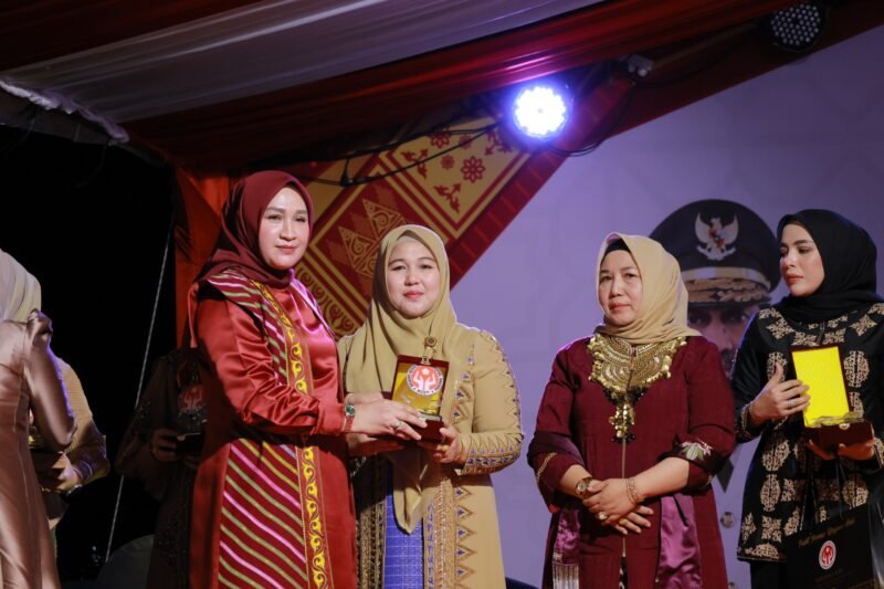 Ketua Dekranasda Aceh Besar Hj Rita Mayasari menerima plakat penghargaan dari Ketua Dekranasda Aceh Marlina Muzakir, di Pasar Tani Lampineung, Kecamatan Syiah Kuala, Kota Banda Aceh, Minggu (9/11/2025) malam. FOTO/ MC ACHE BESAR