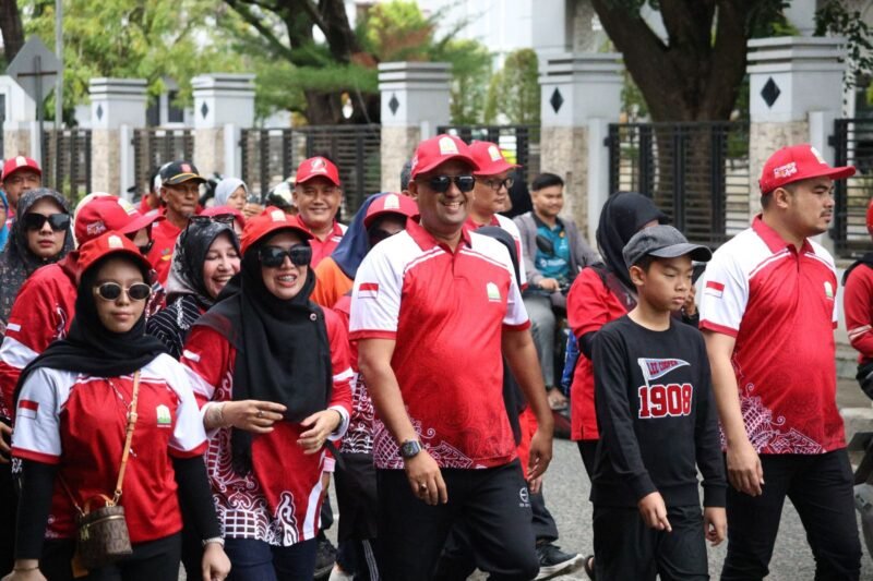 Ratusan peserta Jalan Santai Hari Pahlawan yang digelar Dinas Sosial Aceh tetap bersemangat meski diguyur hujan di Banda Aceh, Minggu 23/11/2025. (Foto: Dok. Ist) 