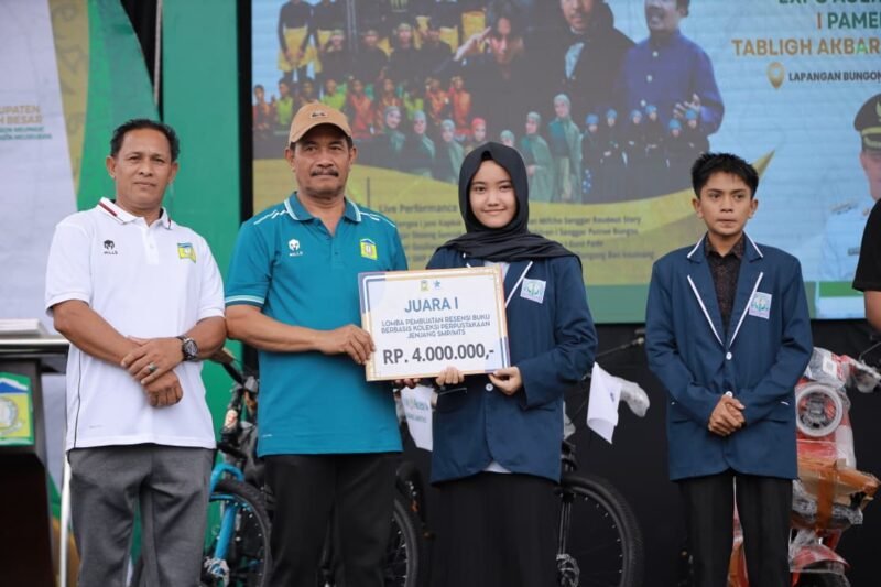 Wakil Bupati Aceh Besar, Drs Syukri A Jalil menyerahkan doorprize paket umroh kepada peserta jalan sehat memperingati Uroe Lahe (Hari Jadi) ke-69 Kabupaten Aceh Besar di Lapangan Bungoeng Jeumpa, Kota Jantho, Minggu (23/11/2025). FOTO/PROKOPIM PEMKAB ACEH BESAR