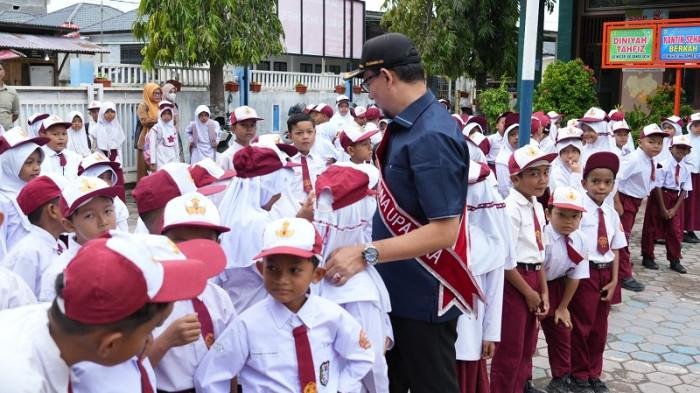 Wakil Ketua DPRK Banda Aceh, Dr Musriadi menyapa murid usai menjadi pembina upacara bendera di SDN 66 Ilie Banda Aceh pada Senin 29/9/2025 (Foto:Dok.Ist)