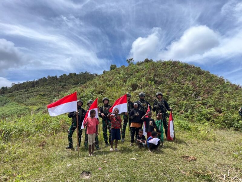 Personel Satgas Yonif 112/DJ Pos KP 55 berjalan beriringan dengan anak-anak Papua menuju lokasi 'Pohon Satu' di Distrik Mulia, Kabupaten Puncak Jaya, Senin (15/12/2025).
