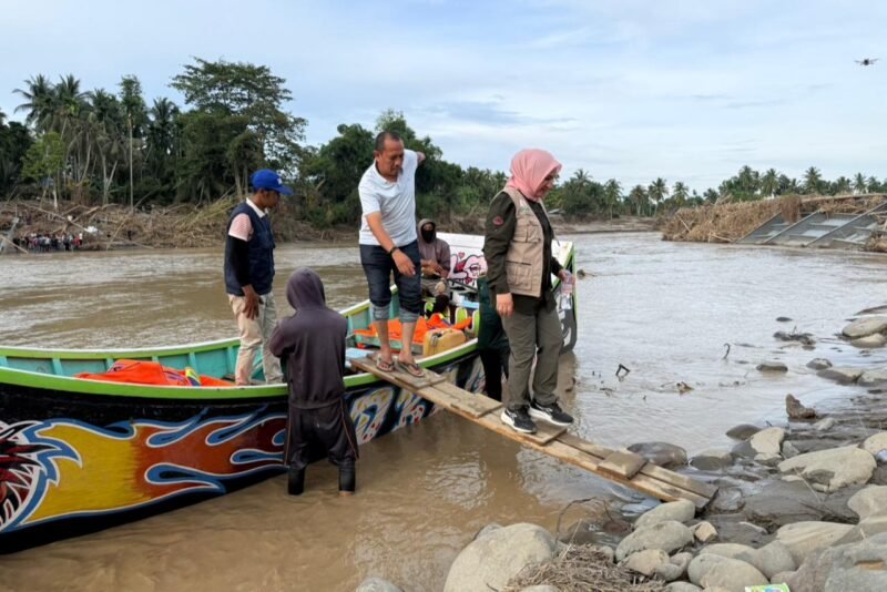 Ketua TP PKK Aceh, Marlina Muzakir (Kak Na), menumpang perahu nelayan menyeberangi Krueng Peusangan untuk mengantarkan bantuan ke Gampong Kubu, Kecamatan Peusangan Siblah Krueng, yang terisolir akibat putusnya jembatan penghubung, Minggu (14/12/2025).