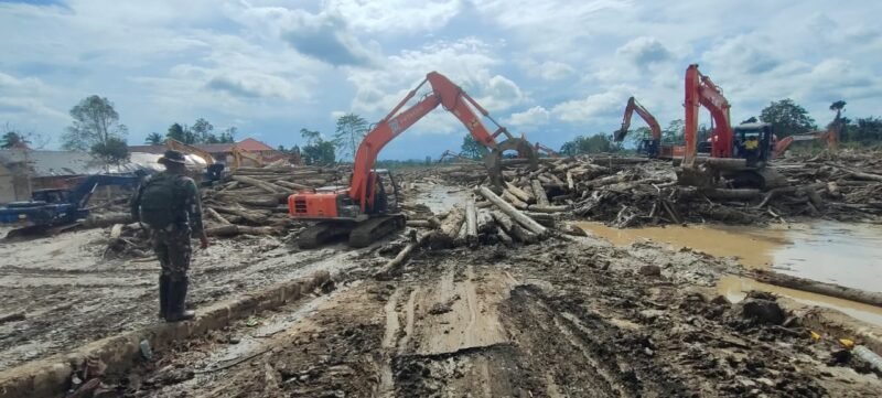 Sejumlah prajurit TNI dari Satgas Gunbencal bersama petugas lintas instansi mengerahkan alat berat untuk mengevakuasi tumpukan kayu gelondongan dan material lumpur di kawasan Ponpes Darul Mukhlisin, Aceh Tamiang, Rabu (24/12/2025).