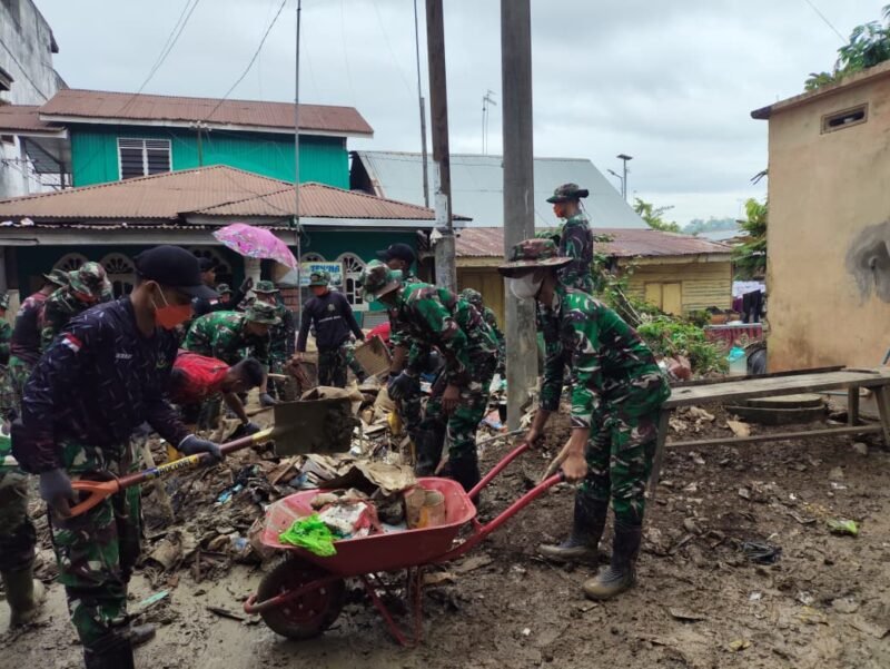 Sejumlah personel Yonif 115 bahu-membahu membersihkan sisa lumpur dan material banjir di area Pasar Kuala Simpang, Aceh Tamiang, Sabtu (27/12/2025). 