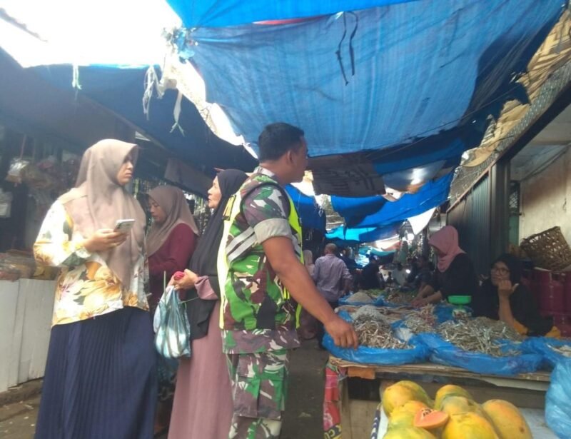 Babinsa Koramil 09/Ulee Kareng Serka Khairil A berdialog dengan pedagang saat memantau harga kebutuhan pokok di Pasar Ulee Kareng, Banda Aceh, Selasa (20/1/2026), guna memastikan stabilitas harga dan ketersediaan bahan pangan bagi masyarakat.