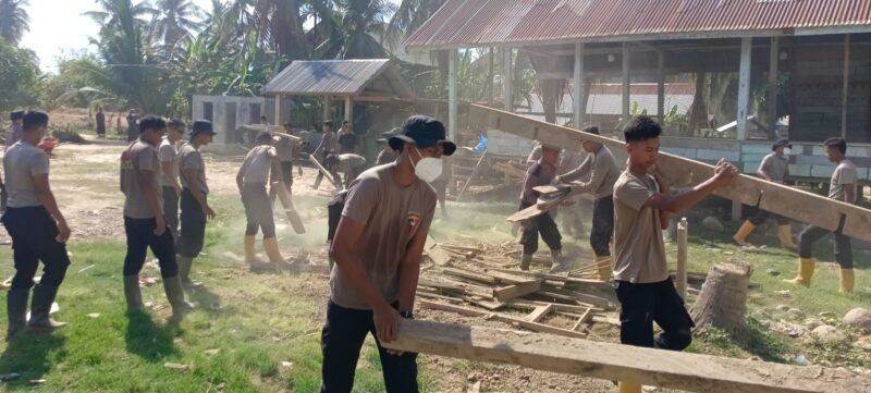 Personel Polres Lhokseumawe bersama BKO Brimob Polda Kaltim bergotong royong membersihkan Balai Pengajian Darul Ilmi di Desa Teumpok Berandang, Muara Batu, Aceh Utara, pascabanjir, Sabtu (31/1/2026).