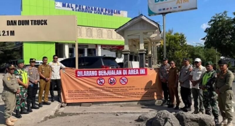 Kasatpol PP dan WH Aceh Besar, Muhajir SSTP MPA, memasang spanduk imbauan larangan berjualan di fasilitas umum di kawasan MPP Aceh Besar, Lambaro, Kecamatan Ingin Jaya, Senin (26/1/2026).