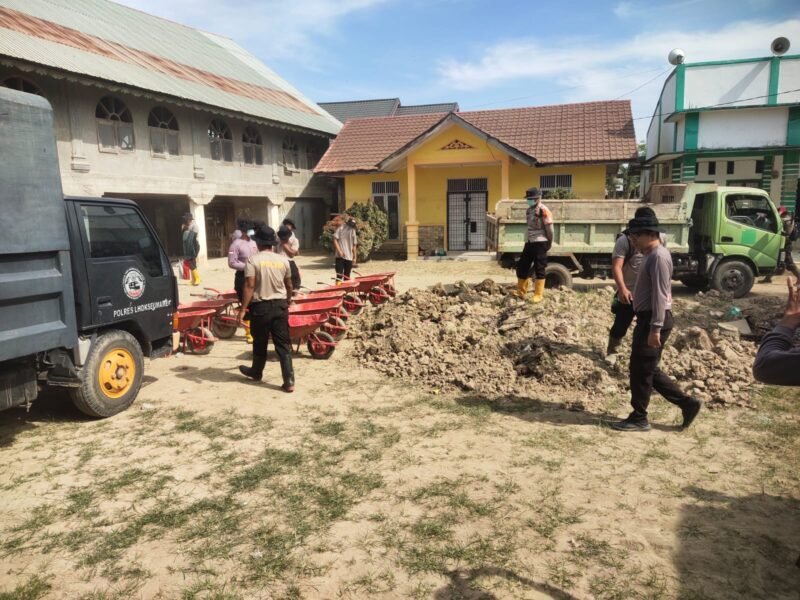 Personel Polres Lhokseumawe bersama BKO Brimob Polda Kaltim melakukan gotong royong pembersihan sisa lumpur pascabanjir di Komplek Pemerintahan Desa Lagang, Kecamatan Sawang, Aceh Utara, Senin (9/2/2026).