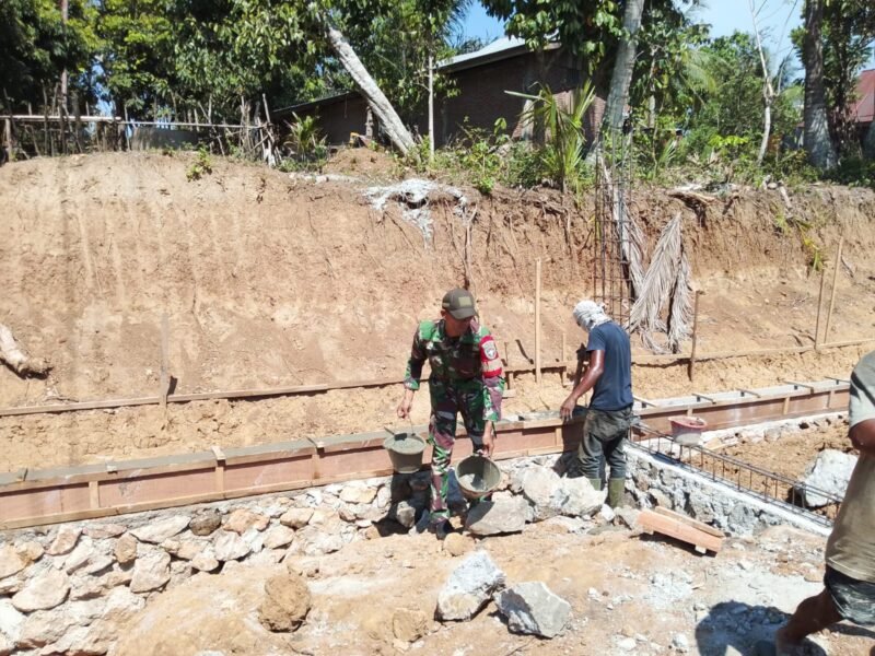 Babinsa Koramil 01/Seulimeum Kodim 0101/Kota Banda Aceh, Serda M. Iskandar, bersama warga Desa Lampantee bergotong royong membantu pembangunan rumah di Kecamatan Seulimeum, Aceh Besar, Kamis (12/02/2026).