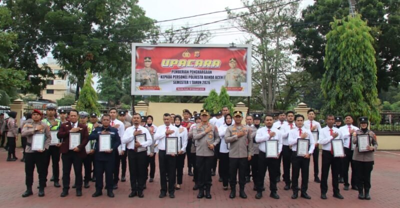 Kapolresta Polresta Banda Aceh Kombes Pol Andi Kirana menyerahkan penghargaan kepada 50 personel berprestasi serta satu petugas Avsec Bandara Sultan Iskandar Muda dalam upacara di halaman Mapolresta, Senin (16/2/2026).