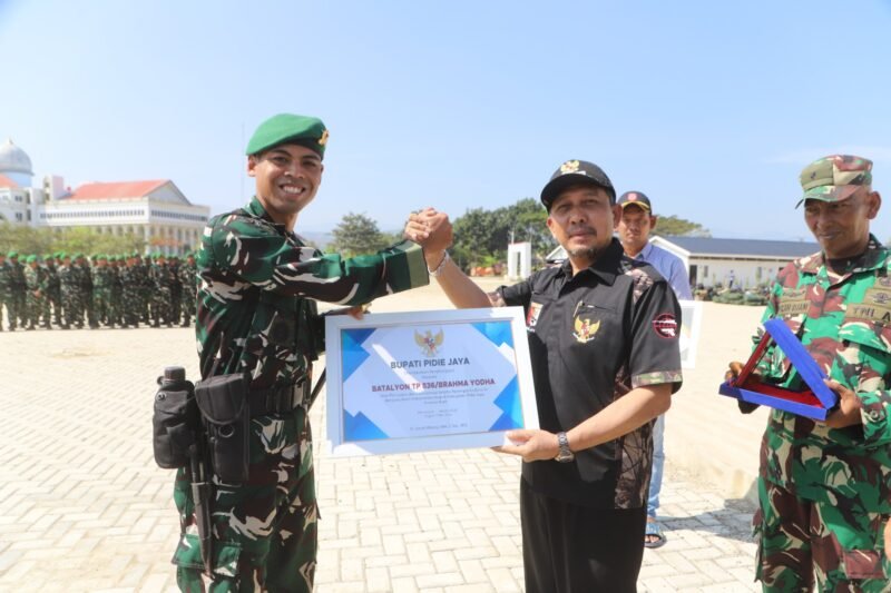 Bupati Pidie Jaya H. Sibral Malasyi menyerahkan penghargaan kepada Danyonif TP 836/Brahma Yodha, Letkol Inf Faishal Riza, saat upacara pelepasan Satgas Gulbencal TNI usai menuntaskan operasi pemulihan pasca bencana hidrometeorologi di Lapangan Gedung MTQ Pidie Jaya, Sabtu (7/3/2026).