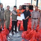 Kalaksa Badan BPBD Aceh Besar, Ridwan Jamil SSos MSi, menyerahkan secara simbolis daging sapi kepada Camat Krueng Barona Jaya, Sayusi, SE untuk masyarakat terdampak banjir di Pos Induk Sibreh, Kecamatan Sukamakmur, Aceh Besar, Kamis (19/03/2026). FOTO/MC ACEH BESAR