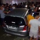 Aparat kepolisian memasang garis polisi pada mobil Honda Jazz BK 1508 JI di Gampong Keude Luengputu, Pidie Jaya, Selasa (24/3/2026). Penemuan dua jenazah di dalam mobil yang masih menyala ini diduga kuat akibat keracunan gas karbon monoksida (CO).