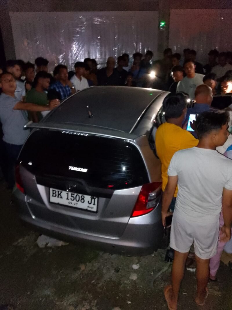 Aparat kepolisian memasang garis polisi pada mobil Honda Jazz BK 1508 JI di Gampong Keude Luengputu, Pidie Jaya, Selasa (24/3/2026). Penemuan dua jenazah di dalam mobil yang masih menyala ini diduga kuat akibat keracunan gas karbon monoksida (CO).