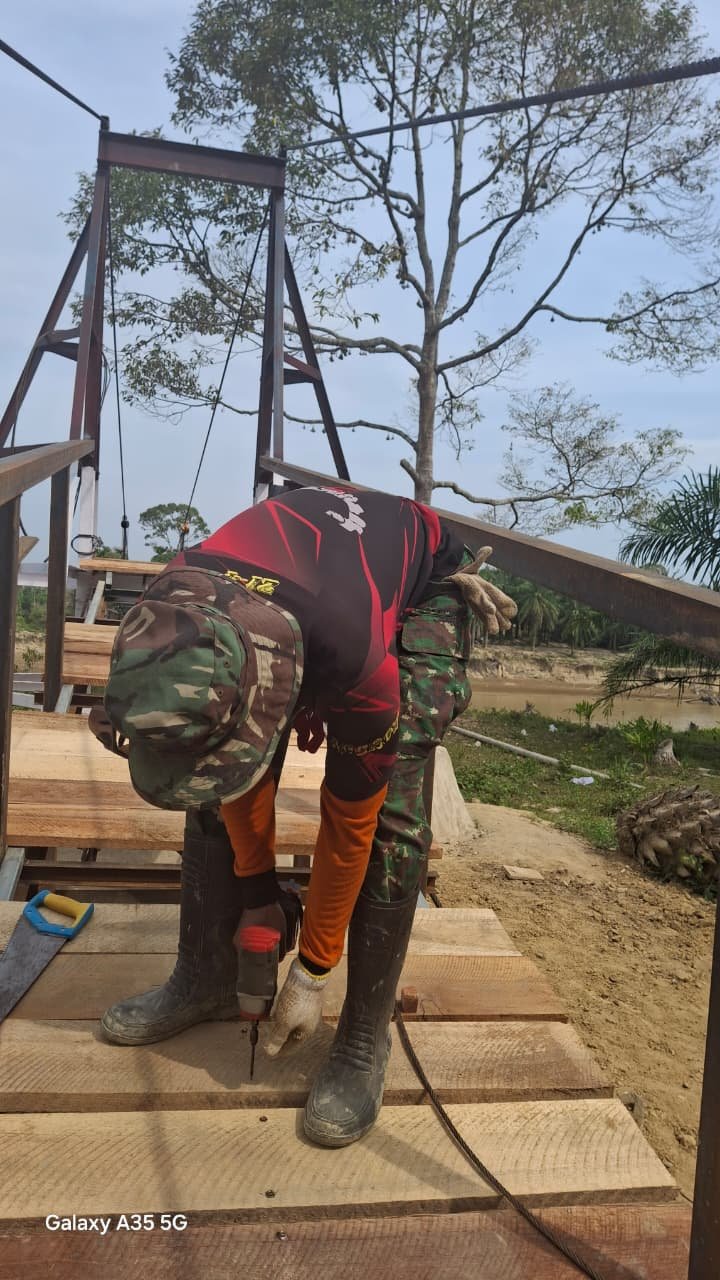 Personel TNI dari Kodam Iskandar Muda bersama warga bahu-membahu mempercepat pembangunan Jembatan Gantung Perintis Garuda di atas Sungai Tamiang, Aceh Tamiang. Hingga Jumat (27/3/2026), proyek vital sepanjang 240 meter ini telah mencapai progres signifikan 77,90 persen dan material telah terdistribusi 100 persen.