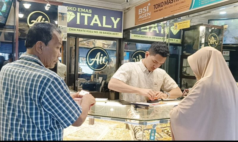 Seorang pedagang emas di kawasan Pasar Aceh sedang menunjukkan perhiasan emas kepada calon pembeli, Selasa (31/3/2026). Pasca Idulfitri 1447 Hijriah, warga Banda Aceh terpantau tetap antusias mendatangi toko emas meskipun harga sedang mengalami koreksi tajam ke angka Rp8,1 juta per mayam.