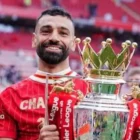 Mohamed Salah memberikan gestur hormat ke arah tribun The Kop. Setelah mendedikasikan tahun-tahun terbaiknya bagi Liverpool, 'Sang Raja Mesir' dipastikan akan menuntaskan pengabdiannya di Merseyside pada akhir musim 2025/2026 dengan segudang rekor dan trofi.