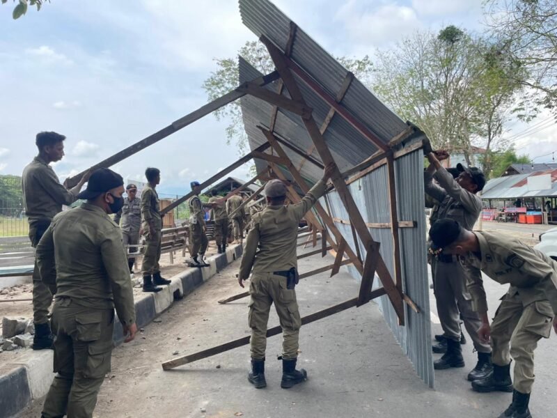 Petugas Satpol PP dan WH Aceh Besar membongkar bangunan pondok pedagang yang berada di trotoar jalan aksen Bandara SIM, Blang Bintang, Aceh Besar, Senin (6/4/2026). FOTO/ MC ACEH BESAR