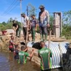 Personel TNI dari Kodim 0107/Aceh Selatan bersama warga Desa Raket dan Desa Pasi Rasian bahu-membahu melakukan pemasangan papan mal dan penyusunan batu untuk konstruksi Jembatan Aramco di Kecamatan Pasiraja, Aceh Selatan, Selasa (07/04/2026).