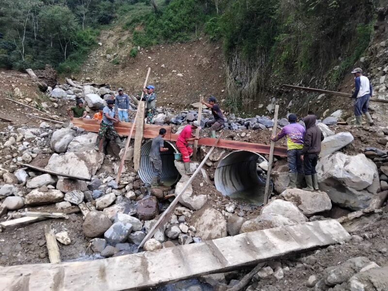 Pgs. Danramil 04/Pintu Rime Gayo, Pelda Yulianto, bersama warga Desa Uning Mas bergotong royong mempercepat pemasangan gorong-gorong Jembatan Aramco di Kecamatan Pintu Rime Gayo, Bener Meriah, Kamis (16/4/2026). 