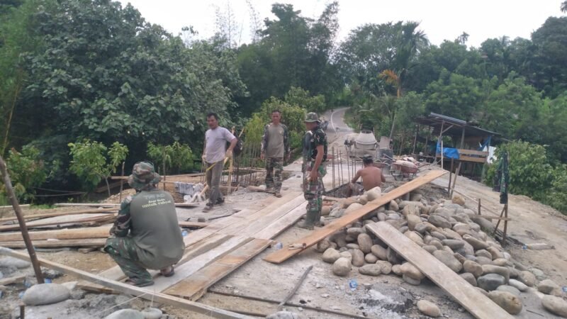 Personel Koramil 0108-03/Badar bersama warga Desa Kumbang Jaya bahu-membahu mengangkut material batu untuk pembangunan Jembatan Gantung Perintis Garuda di Aceh Tenggara, Senin (20/4/2026).