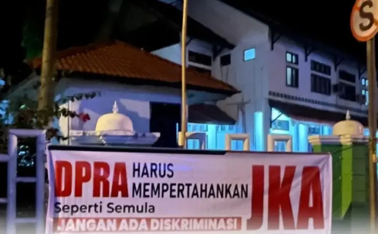 Spanduk berisi penolakan terhadap pembatasan JKA terpasang di pagar DPRK Aceh Barat, Sabtu (18/4/2026) dini hari. Aksi ini mencerminkan meningkatnya keresahan masyarakat terhadap kebijakan layanan kesehatan di Aceh.