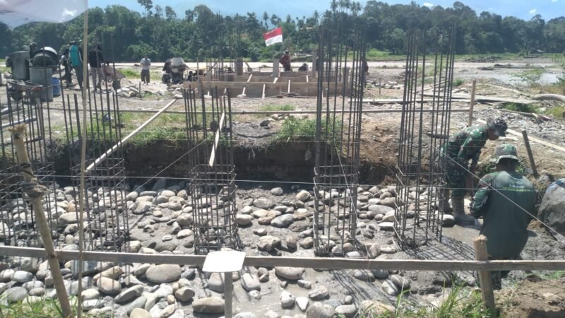 Personel Kodim 0108/Aceh Tenggara bersama warga bahu-membahu melakukan pengecoran pondasi Jembatan Gantung Perintis Tahap II di Desa Gulo, Kecamatan Darul Hasanah, Sabtu (09/05/2026).