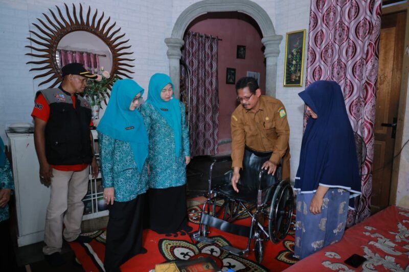 Ketua TP-PKK Aceh Besar, Hj. Rita Mayasari, melakukan foto bersama usai serahkan bantuan satu unit kursi roda dan Bantuan sosial kepada Ainal Mardhiah (74), di Gampong Lampenerut Ujong Blang, Kecamatan Darul Imarah, Aceh Besar, Selasa (12/05/2026). FOTO/MC ACEH BESAR
