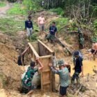 Personel Satgas TMMD Reguler ke-128 Kodim 0117/Aceh Tamiang bersama warga Desa Suka Makmur bergotong royong membangun kupingan gorong-gorong untuk memperkuat ketahanan infrastruktur jalan desa, Minggu (17/5/2026).