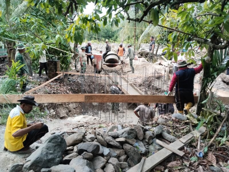 Personel Babinsa Posramil Lawe Sumur jajaran Kodim 0108/Aceh Tenggara bersama warga Desa Teger Miko bergotong royong melakukan pengecoran pondasi tapak utama Jembatan Gantung Perintis Garuda di Kecamatan Lawe Sumur, Aceh Tenggara, Jumat (22/5/2026).