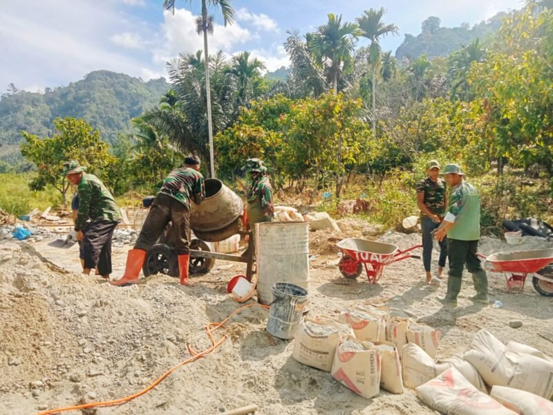 Personel Babinsa Kodim 0108/Aceh Tenggara bersama warga Desa Teger Miko bahu-membahu mengangkut material dan melakukan pengecoran pondasi tiang pylon Jembatan Gantung Perintis di Kecamatan Lawe Sumur, Aceh Tenggara, Rabu (3/6/2026). 