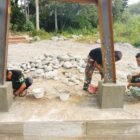 Personel Babinsa Posramil Lawe Sumur Kodim 0108/Aceh Tenggara bersama warga Desa Teger Miko bahu-membahu melakukan pemlesteran pondasi menara pylon Jembatan Gantung Perintis, Selasa (9/6/2026).