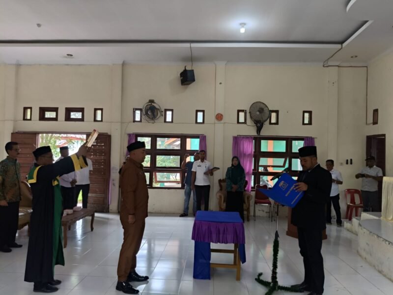 Camat Lhoknga, Ziyadinur, S.STP (kanan), saat memimpin prosesi pengambilan sumpah jabatan Darwin Kamaruddin sebagai Keuchik Gampong Lamkruet di Aula Kantor Camat Lhoknga, Aceh Besar, Selasa (10/6/2026). 