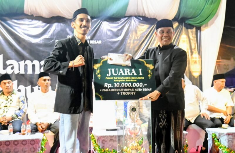 Bupati Aceh Besar, H Muharram Idris menyerahkan piala kepada juara I pawai mobil hias menyambut Tahun Baru Islam 1448 H di depan Masjid Jamik Lambaro, Kecamatan Ingin Jaya, Aceh Besar, Senin (15/06/2026) malam. FOTO/MC ACEH BESAR