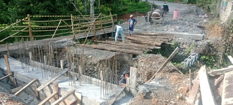 Personel Babinsa Kodim 0108/Aceh Tenggara bersama warga Desa Lawe Sikap 1, Kecamatan Babussalam, bergotong royong memasang besi penahan rangka utama jembatan beton, Sabtu (27/6/2026).