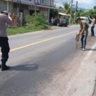 Sejumlah personel Polsek Lhoknga bersama warga bahu-bahu menaburkan pasir di atas tumpahan oli CPO di Jalan Nasional depan BSI Lhoknga, Aceh Besar, Minggu (5/7/2026).