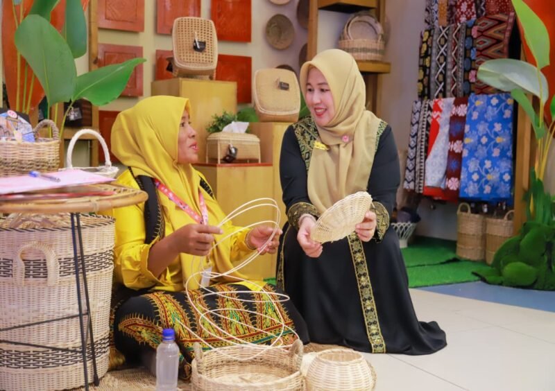 Ketua Dekranasda Aceh Besar Hj Rita Mayasari, memperlihatkan salah satu produk unggulan Stand Dekranasda Aceh Besar pada ajang Pameran Kriya dan Wastra Dekranasda se-Indonesia yang digelar dalam rangka HUT Dekranas ke-46 Tahun 2026 di Trans Studio Mall Makassar, Sulawesi Selatan, Kamis (9/7/2026). FOTO/ PROKOPIM PEMKAB ACEH BESAR