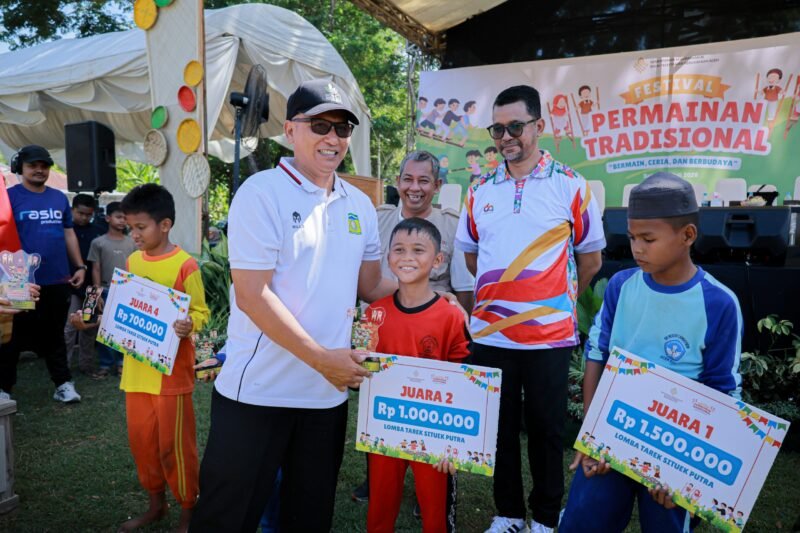 Asisten III Sekretariat Daerah Kabupaten Aceh Besar, Abdullah, S.Sos, menyerahkan hadiah pada pemenan lomba tarek situek saat membuka festival permainan tradisional yang dilaksanakan di Lapangan Desa Lubok Sukon Ingin Jaya, Sabtu (25/7/2026).