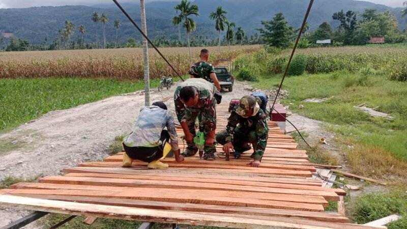 Personel Satgas Kodim 0108/Aceh Tenggara bersama teknisi lapangan memasang papan lantai Jembatan Gantung Perintis di Desa Kuta Ujung, Kecamatan Darul Hasanah, Kabupaten Aceh Tenggara, Jumat (7/8/2026).