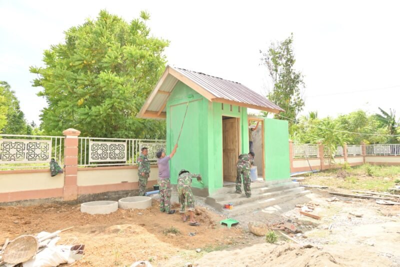 Personel Satgas TMMD ke-129 Kodim 0102/Pidie bersama masyarakat bahu-membahu menyelesaikan tahap finishing pembangunan MCK dan sumur bor di Kecamatan Sakti, Kabupaten Pidie, Senin (10/8/2026).
