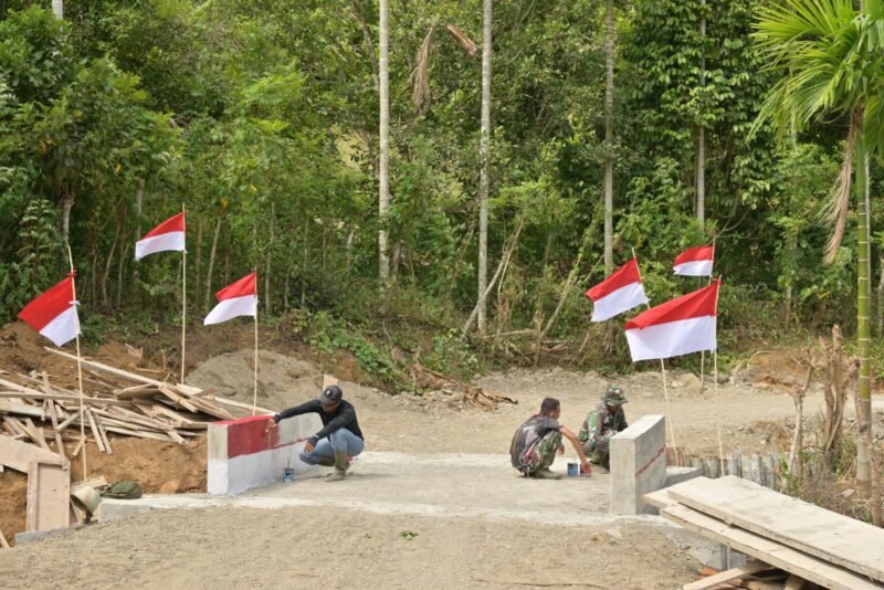 Personel Satgas TMMD ke-129 Kodim 0102/Pidie melakukan pengecatan tembok jembatan box culvert bernuansa merah putih di Desa Lhok Panah, Kecamatan Sakti, Kabupaten Pidie, Selasa (11/8/2026).