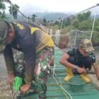 Personel Babinsa Koramil jajaran Kodim 0108/Aceh Tenggara bersama warga Desa Kuta Ujung, Kecamatan Darul Hasanah, bahu-membahu melakukan pengecatan dan pengecoran dalam tahap finishing pembangunan jembatan gantung, Selasa (11/08/2026).
