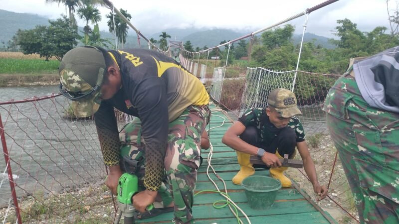 Personel Babinsa Koramil jajaran Kodim 0108/Aceh Tenggara bersama warga Desa Kuta Ujung, Kecamatan Darul Hasanah, bahu-membahu melakukan pengecatan dan pengecoran dalam tahap finishing pembangunan jembatan gantung, Selasa (11/08/2026).