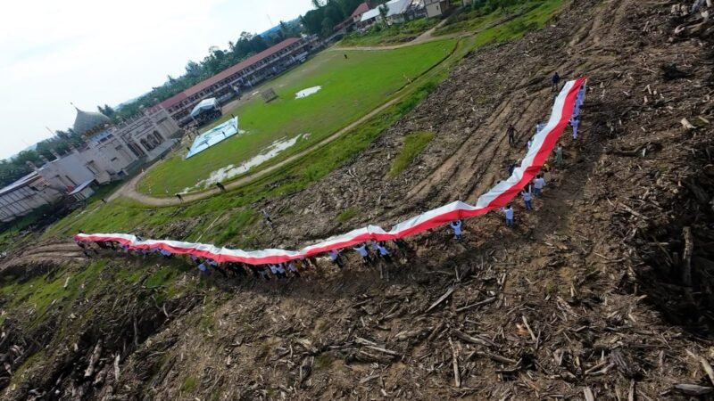 Relawan Bakti BUMN (RBB) 2026 bersama santri dan masyarakat membentangkan bendera Merah Putih sepanjang 81 meter saat Upacara HUT ke-81 RI di Pondok Pesantren Darul Mukhlisin, Aceh Tamiang, Senin (17/8/2026).